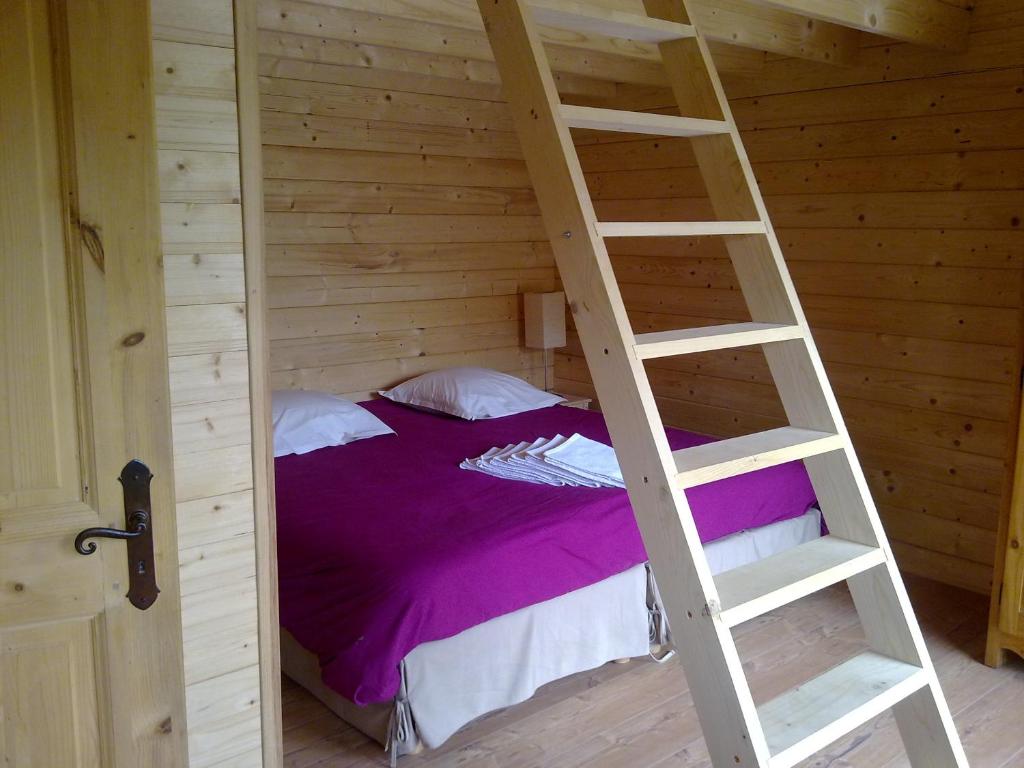 Cama en habitación de madera con escalera en Gites de La Croisée des Chemins - Piscine Chauffée - Spa, Hammam et Sauna, en Izeaux