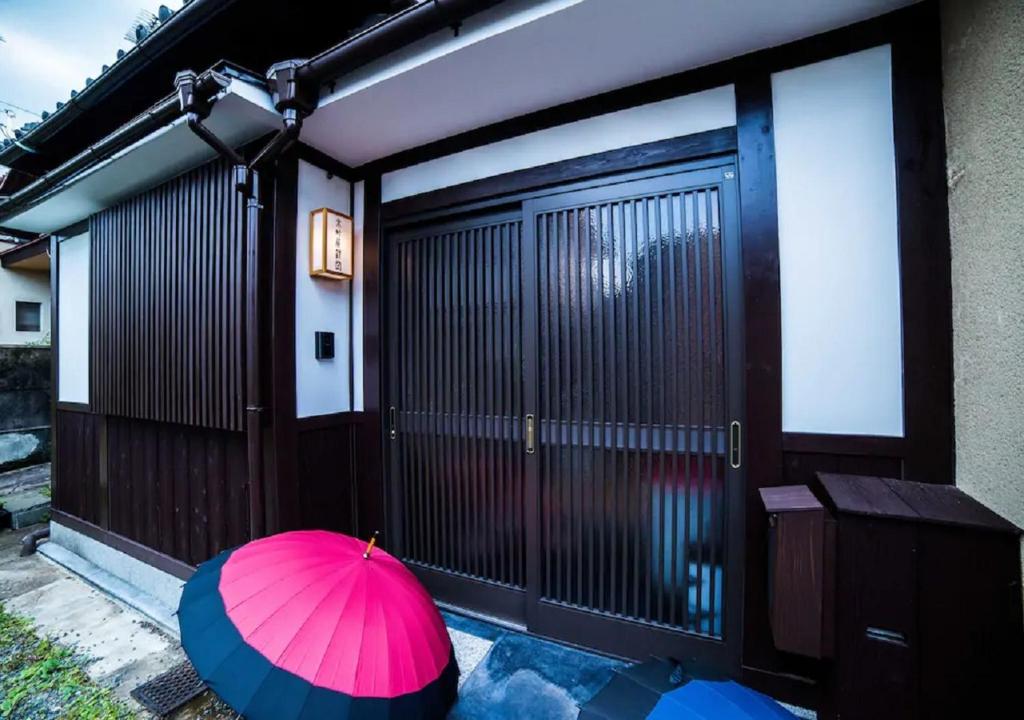 a pink umbrella and two blue umbrellas in front of a garage at Kyoto - House / Vacation STAY 3816 in Kyoto