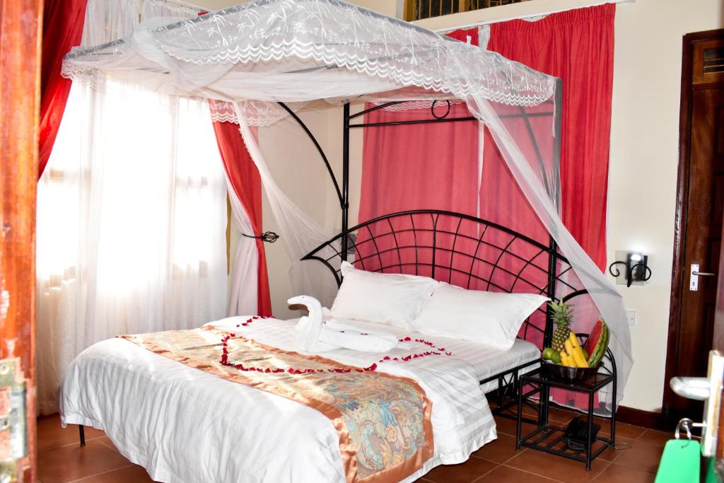 a bedroom with a canopy bed with red curtains at Rates Hotel Mbale in Mbale