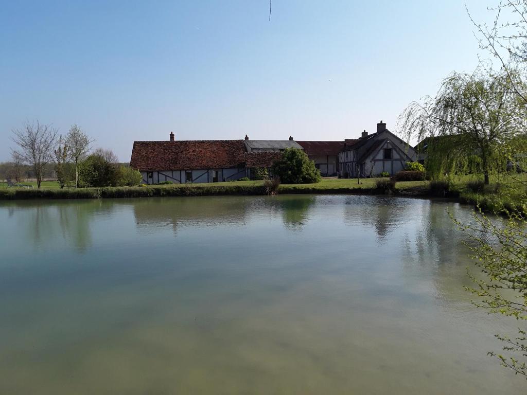 une maison assise à côté d'un lac en face d'une maison dans l'établissement La Belvinière Chambres et table d'hôtes, à Tour-en-Sologne
