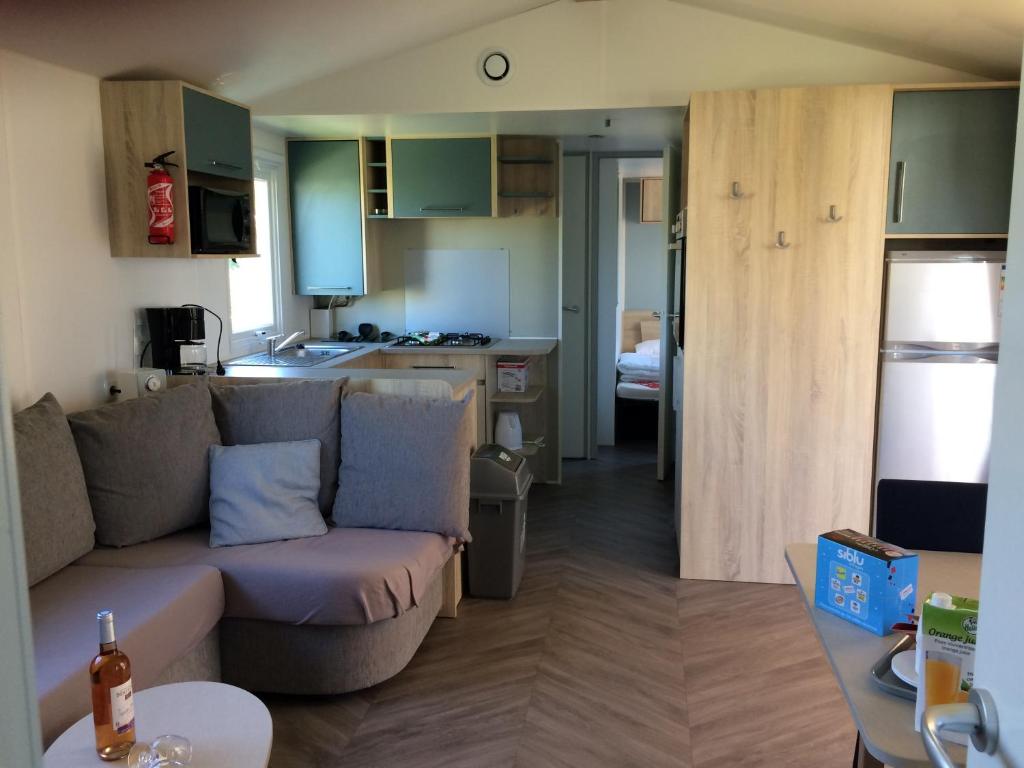 a living room with a couch and a kitchen at camping les charmettes in Les Mathes