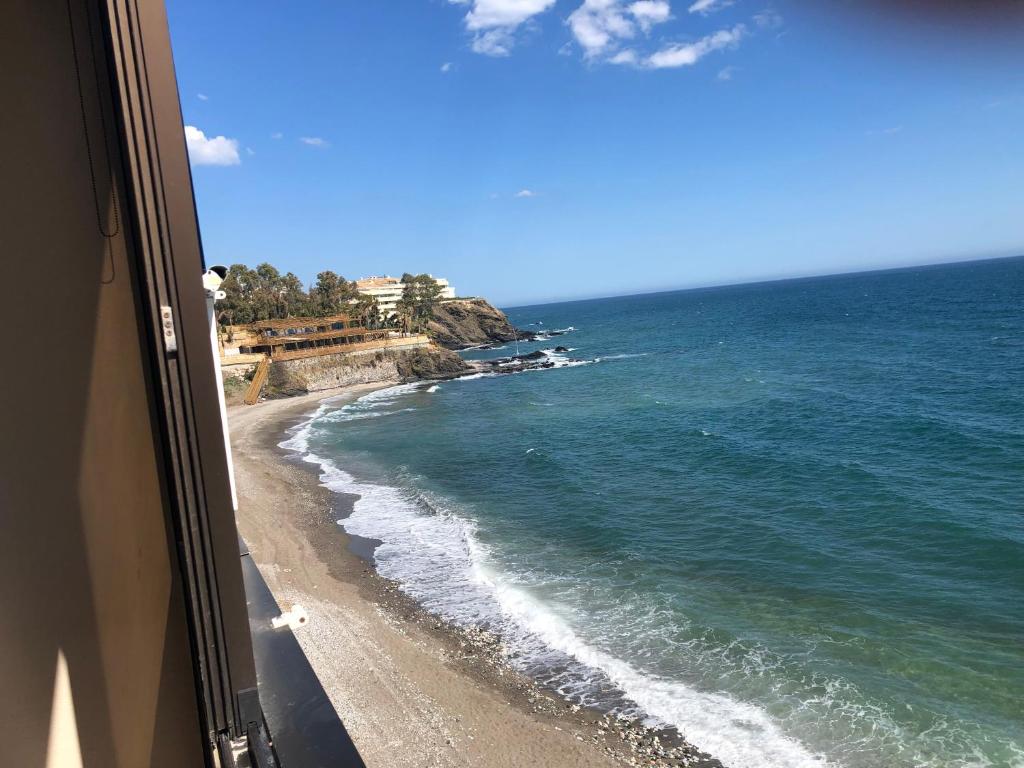 uma vista para a praia a partir de uma janela em Malibu Playa Apartamento em Benalmádena