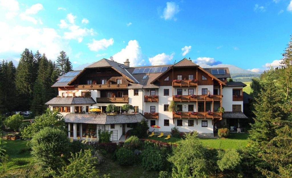 a large house on top of a green field at Hotel Häuserl im Wald in Mariapfarr