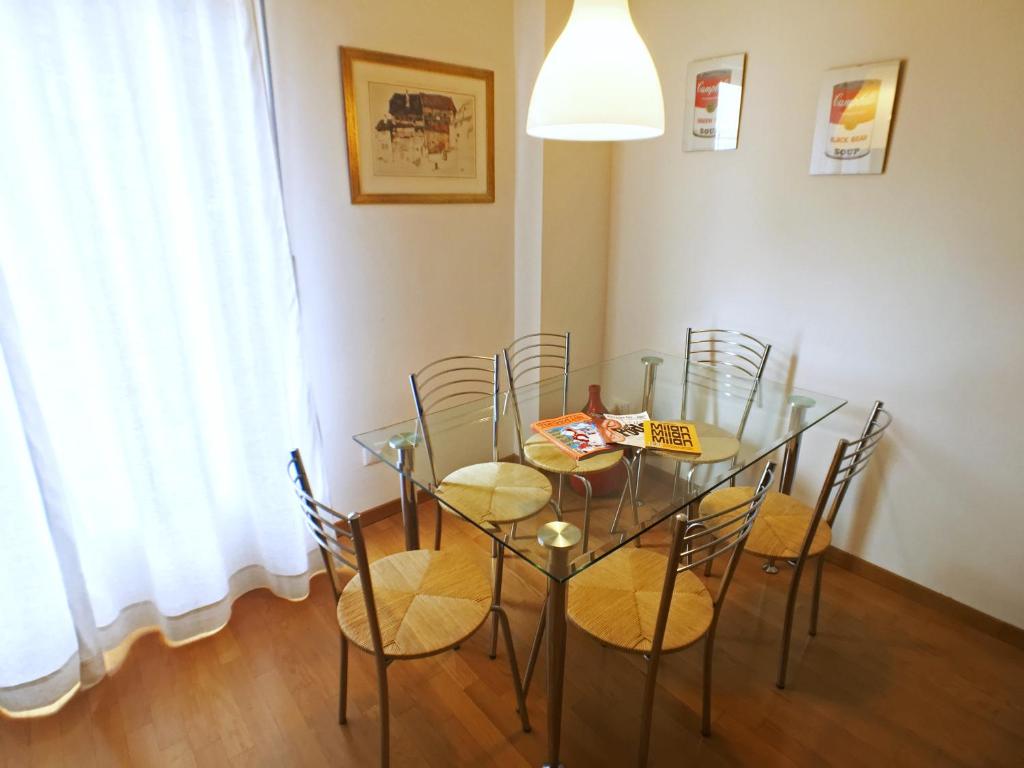 een eetkamer met een glazen tafel en stoelen bij Lario Home in Milaan