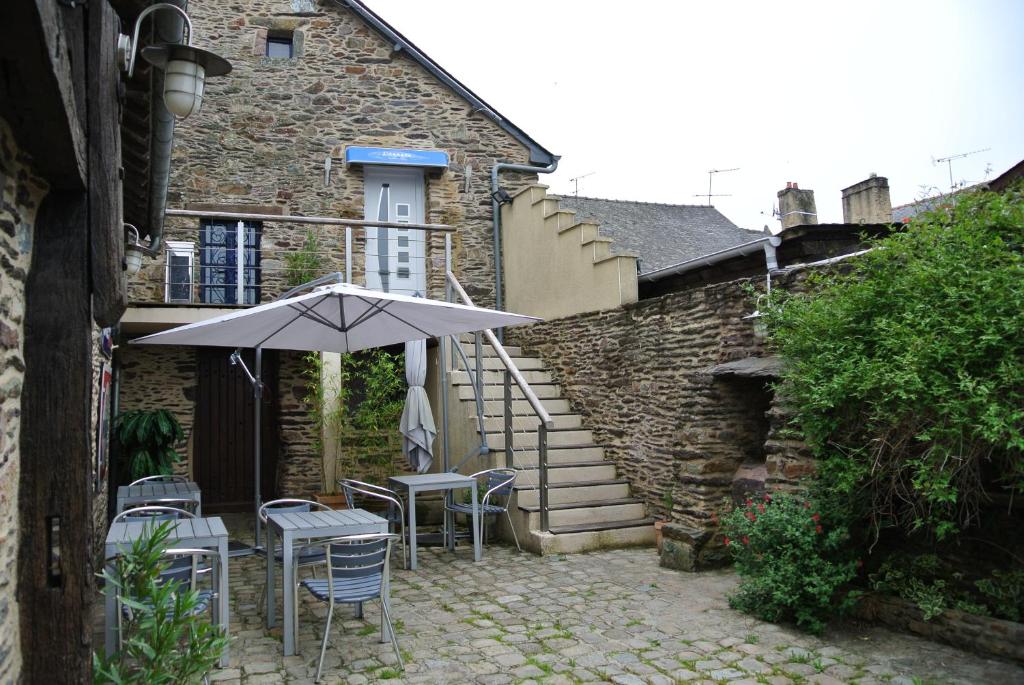um pátio com um guarda-sol e cadeiras e uma escadaria em L 'Annexe em Lohéac