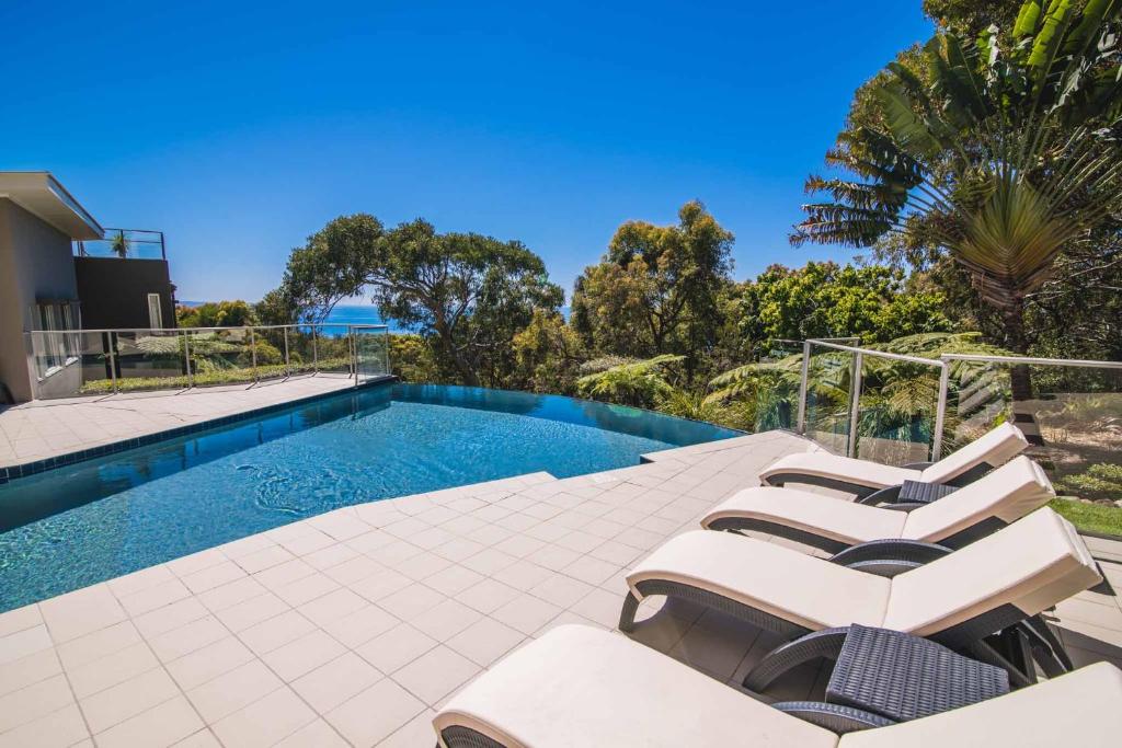 a swimming pool with lounge chairs next to a house at Rainbow Ocean Palms Resort in Rainbow Beach