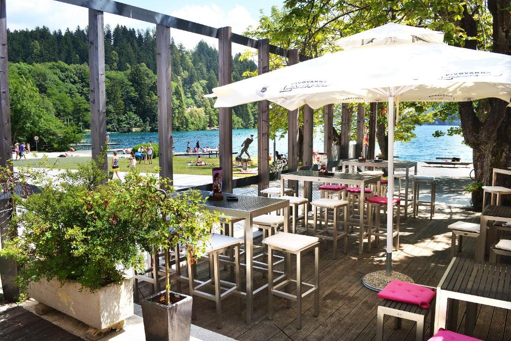 une rangée de tables et de chaises avec parasols à côté de l'eau dans l'établissement Penzion Zaka, à Bled