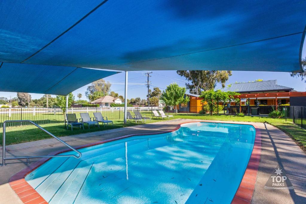 a swimming pool with a blue umbrella over it at Boomerang Way Tourist Park in Tocumwal