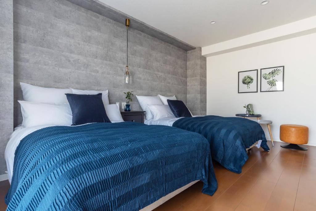 two beds in a bedroom with blue and white sheets at Villa Penthouse Tenma in Osaka