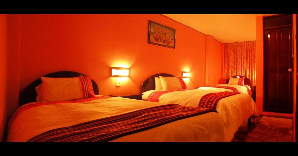 una camera d'albergo con due letti e pareti arancioni di Hotel Margarita a Puno