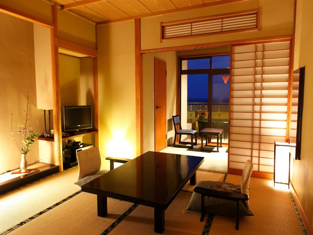 a living room with a table and chairs and a television at Inatori Tokai Hotel Yuen in Higashiizu