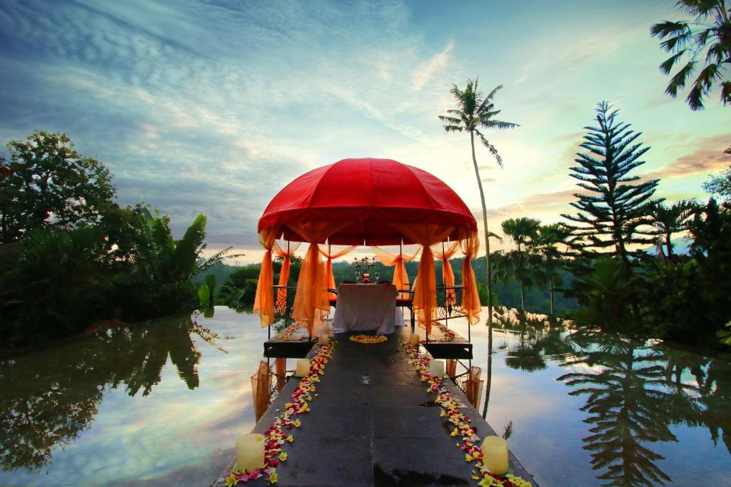 une tente rouge au milieu d'une masse d'eau dans l'établissement Kupu Kupu Barong Villas and Tree Spa by L’OCCITANE, à Ubud