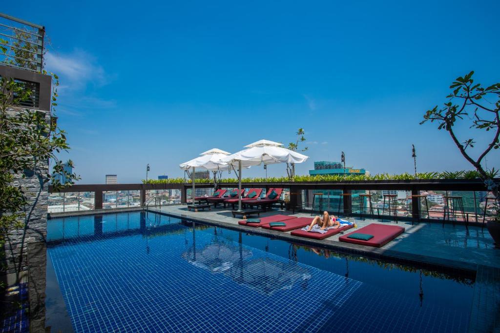 a swimming pool with lounge chairs and umbrellas on a building at V Hotel Phnom Penh in Phnom Penh