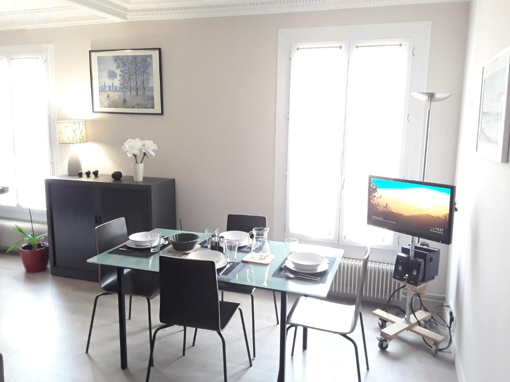 une salle à manger avec une table avec des chaises et une télévision dans l'établissement Apartment with Car Park - Charonne Neighborhood, à Paris