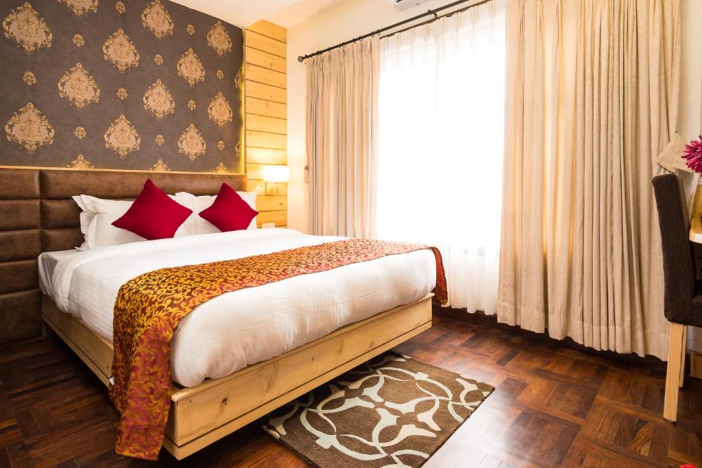 a bedroom with a bed with red pillows and a window at Fresco Retreat in Jawlakhel