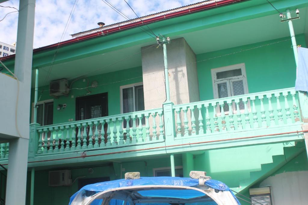 ein grünes Haus mit Balkon auf einer Straße in der Unterkunft jaba in Batumi