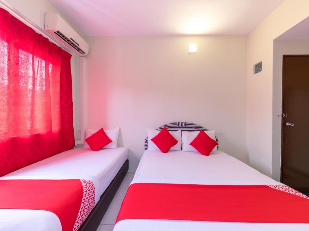 two beds with red pillows in a room at Super OYO 432 My 7days Inn in Johor Bahru