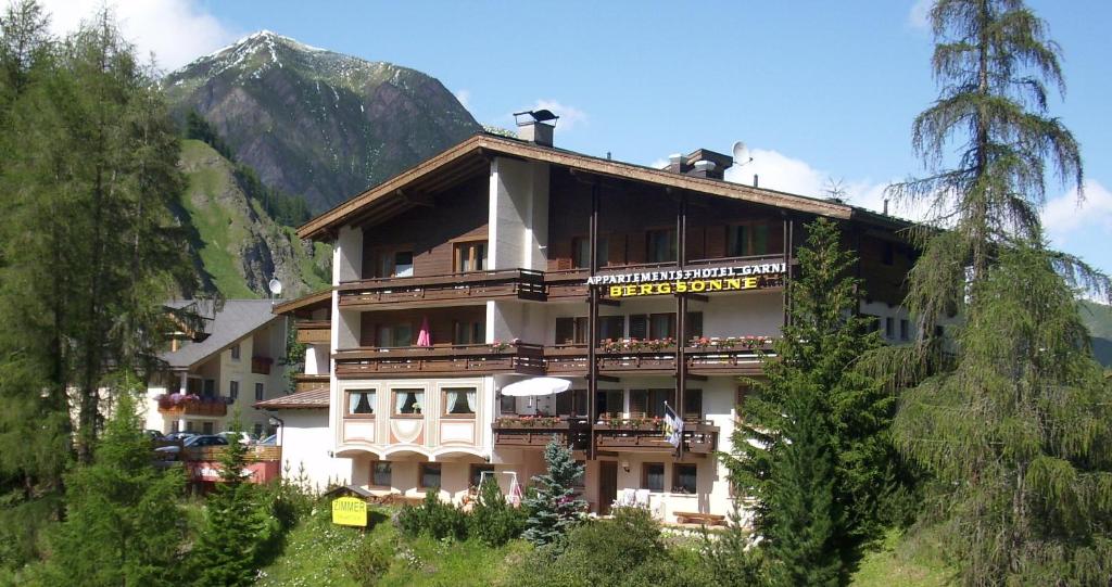ein Gebäude auf einem Hügel mit einem Berg im Hintergrund in der Unterkunft Hotel Garni Bergsonne in Samnaun