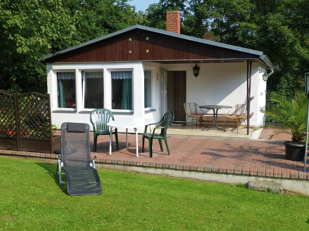 un patio con tavolo, sedie e una casa di Idyllic holiday home in Neinstedt near forest a Thale
