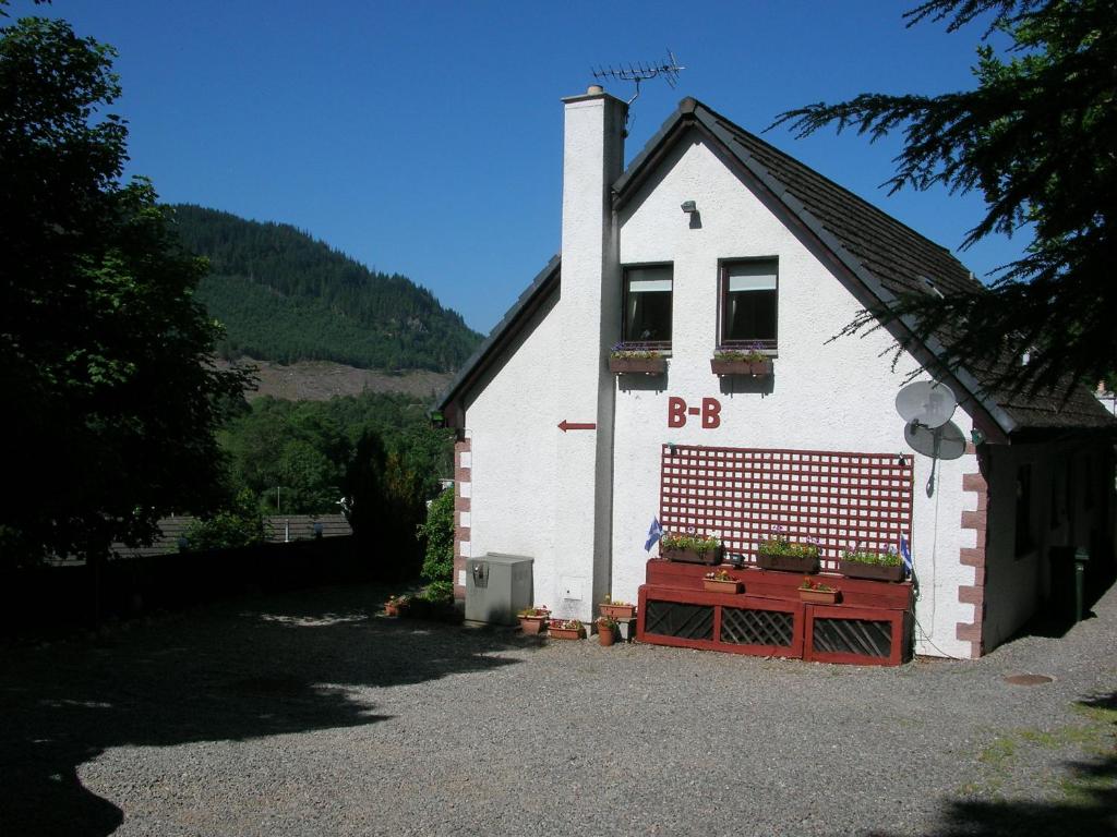 a small white house with a window and plants on it at Darroch View B&B in Invermoriston