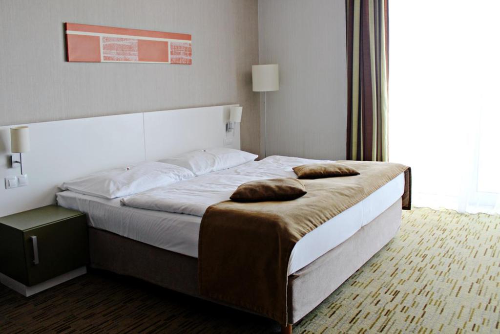 a bedroom with a large bed with two pillows on it at Hotel EMPIRE in Trnava