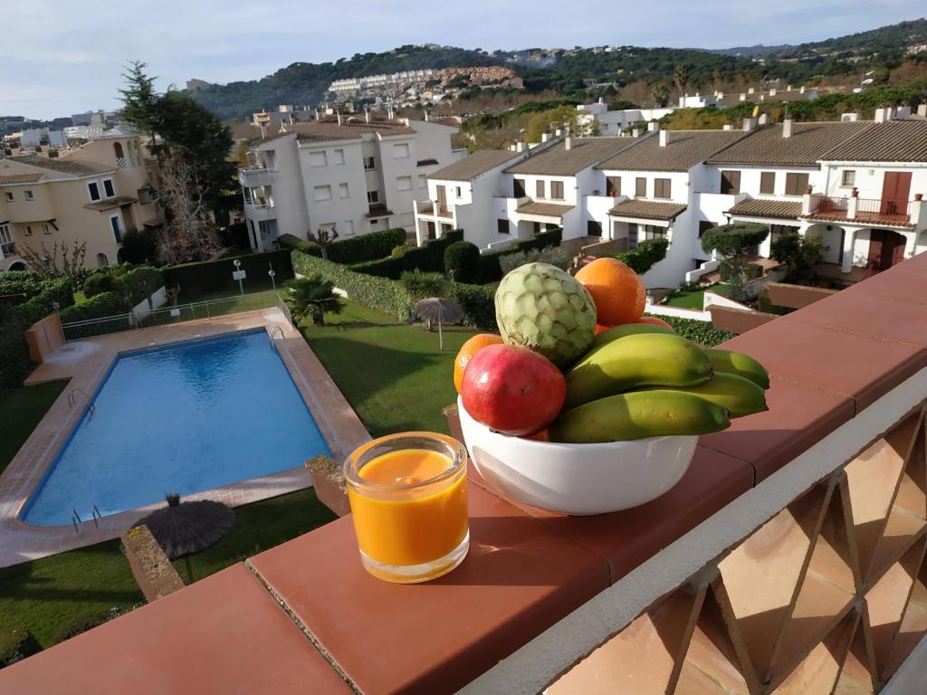 un bol de fruta en una mesa con un vaso de zumo de naranja en Apartamento S'Agaró Fagoi, en S'Agaró