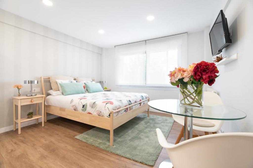 ein Schlafzimmer mit einem Bett und einem Tisch mit einer Blumenvase in der Unterkunft NC APARTMENT in Santiago de Compostela