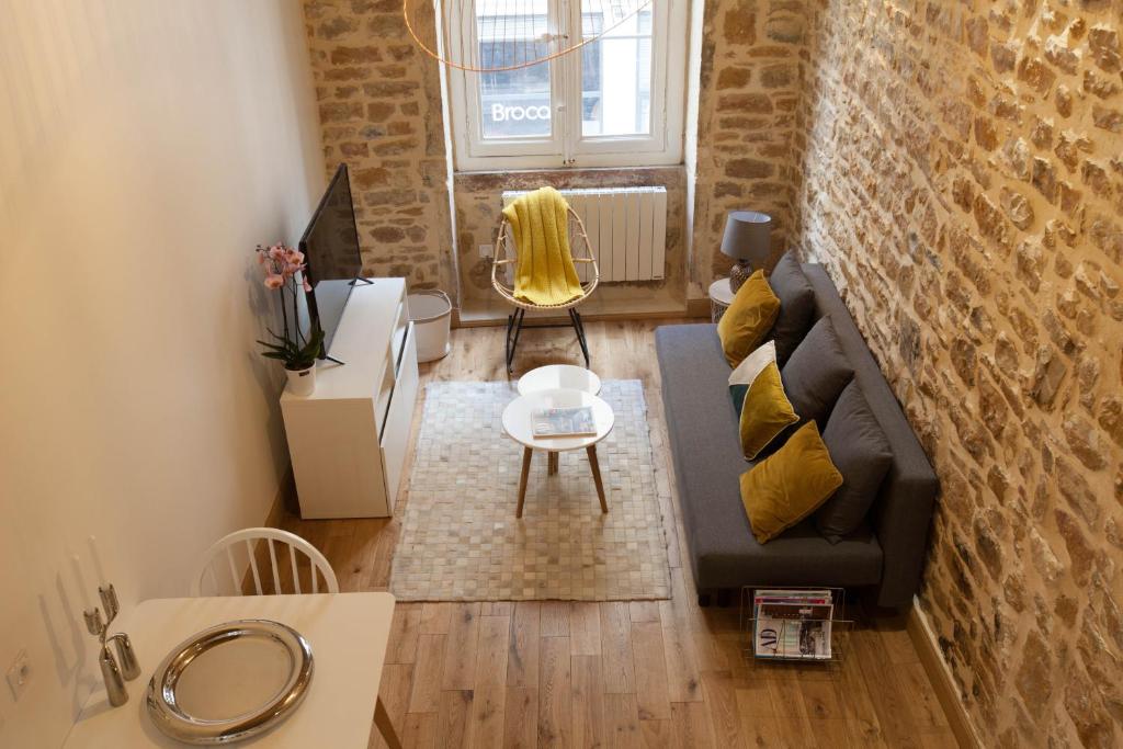 a living room with a black couch and a brick wall at Hamac Suites - Studio Ainay 4 - Hyper centre Lyon in Lyon