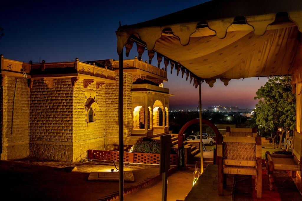 a building with an umbrella on a patio at night at Hotel Rawalkot Jaisalmer in Jaisalmer