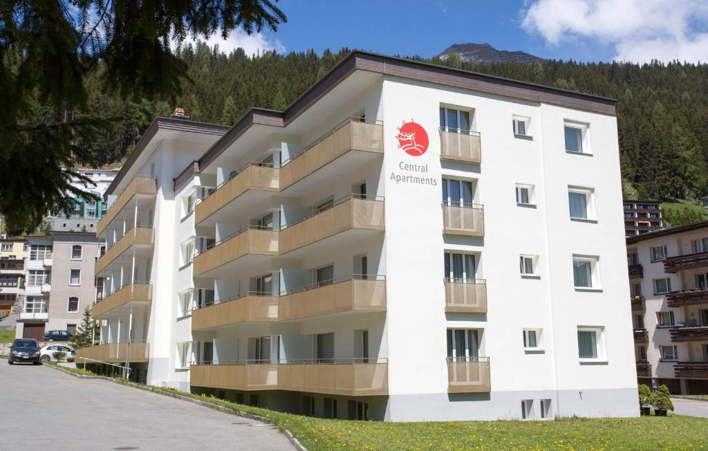 ein weißes Apartmenthaus mit einem roten Schild darauf in der Unterkunft Central Apartments Davos in Davos