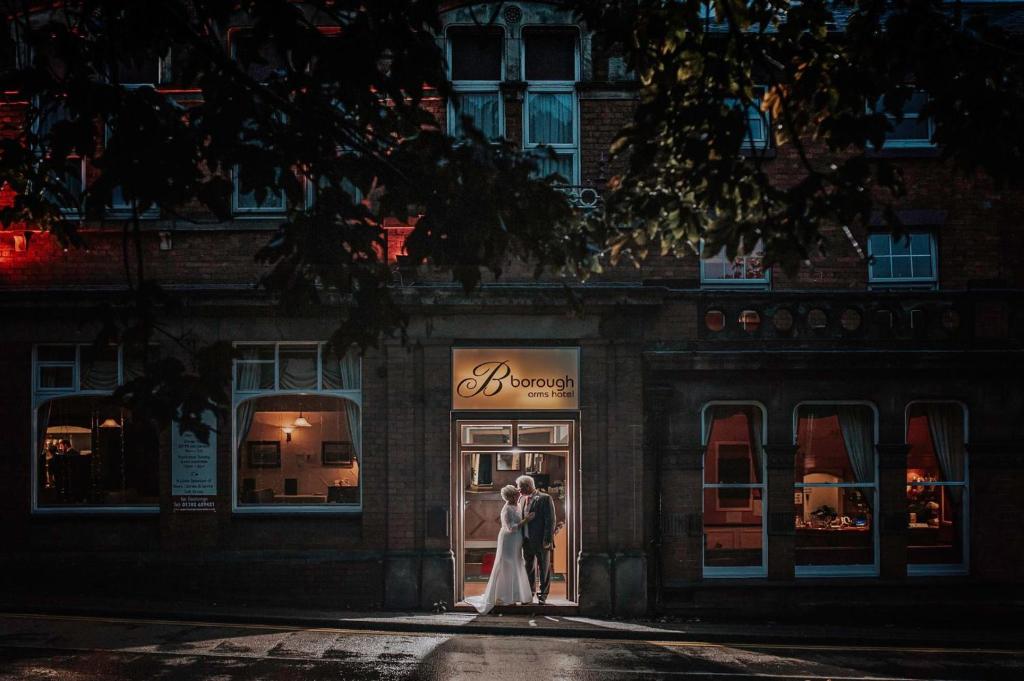 Una novia y un novio parados frente a una tienda en Borough Arms Hotel, en Stoke on Trent
