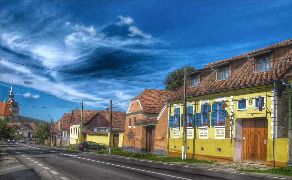 een straat met een geel huis aan de kant van de weg bij Pension Cartref in Saschiz