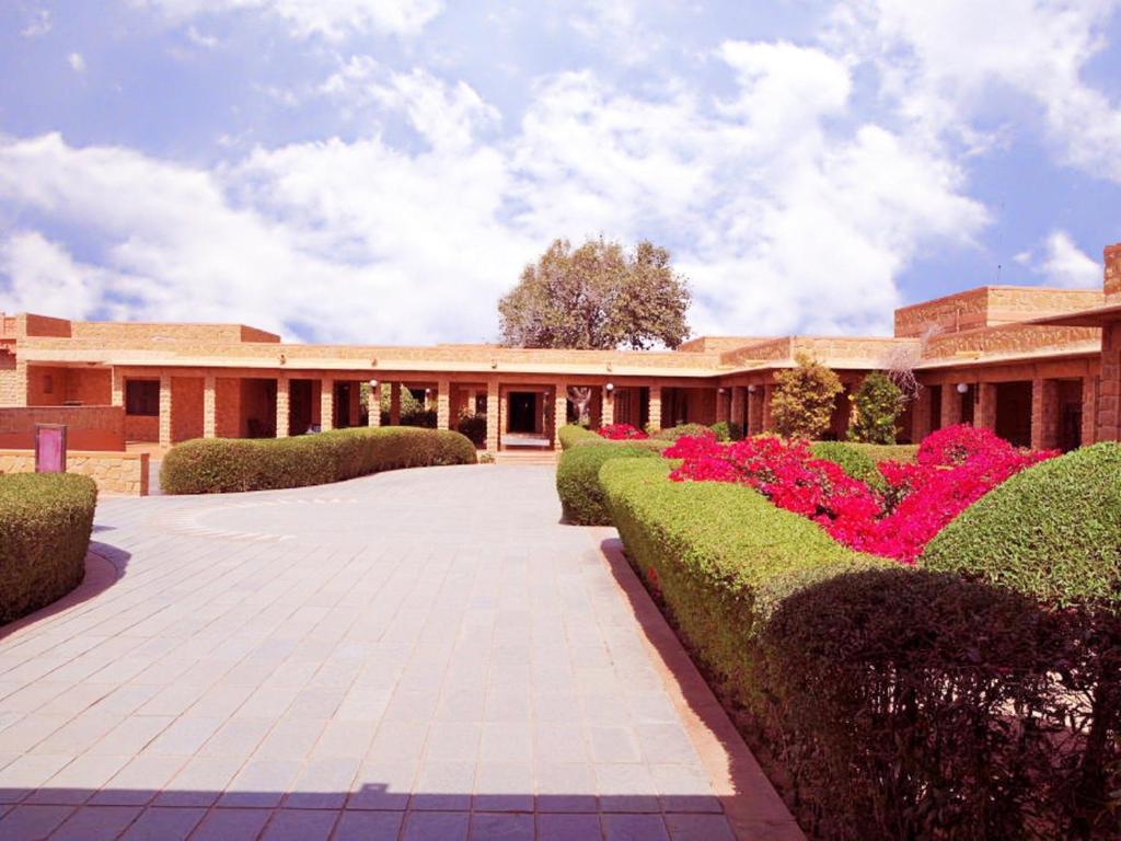 a building with green bushes and pink flowers at Hotel Rawalkot Jaisalmer in Jaisalmer