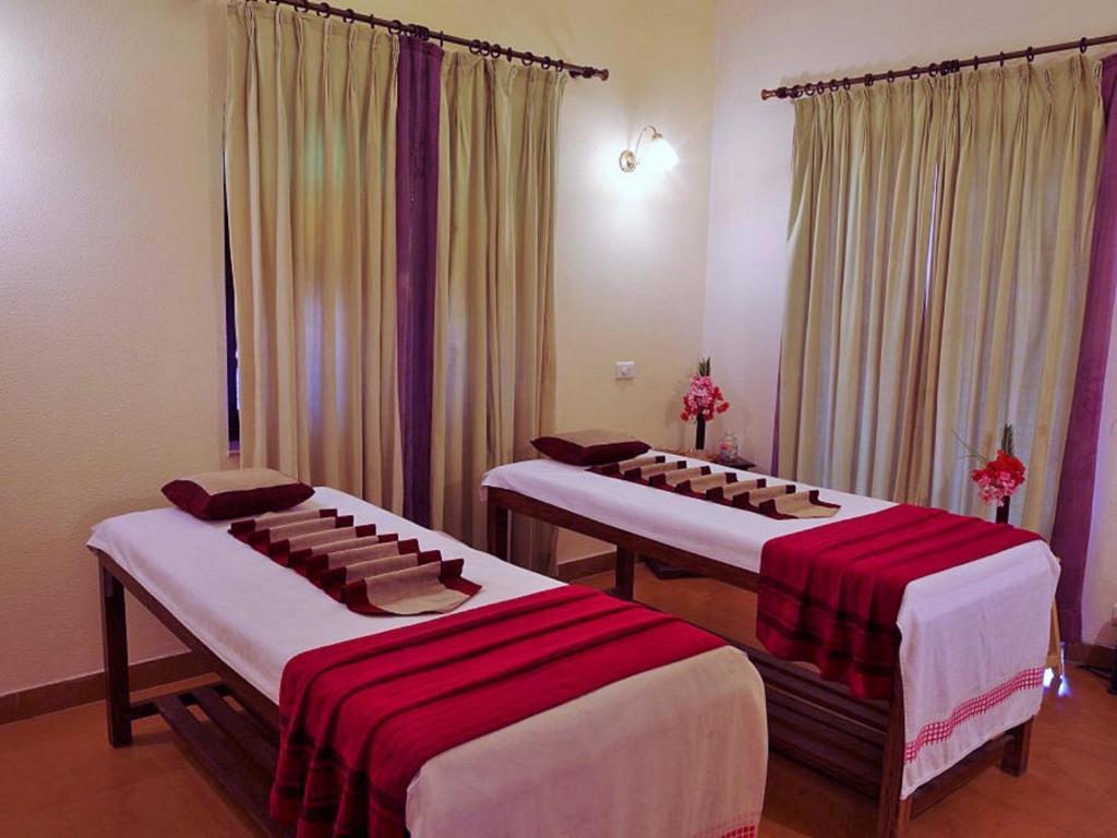 a room with three beds with red and white sheets at Hotel Rawalkot Jaisalmer in Jaisalmer