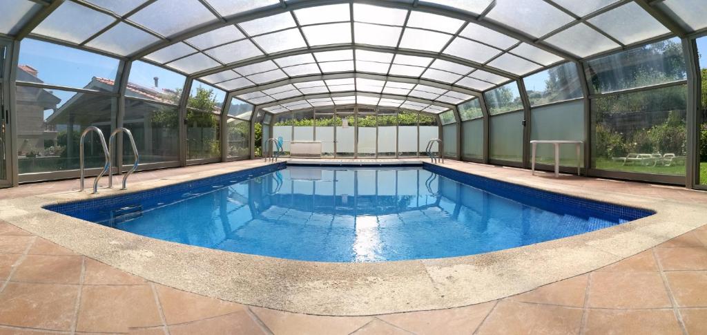 an indoor swimming pool with a glass domed ceiling at Apartamentos Cruceiro in Hio