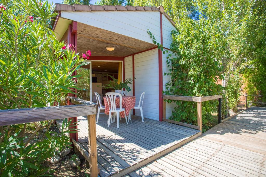 un porche de una casa con mesa y sillas en Bungalows & Rooms - Gît'Ôstal en Carcassonne