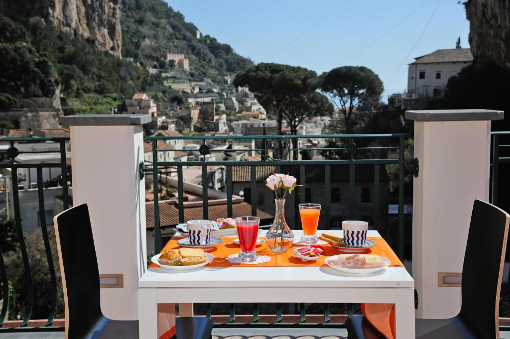 una mesa con comida y bebida en el balcón en B&B Valentì, en Amalfi