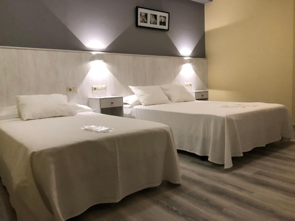 two beds with white sheets in a hotel room at Pension Antonio in Louro