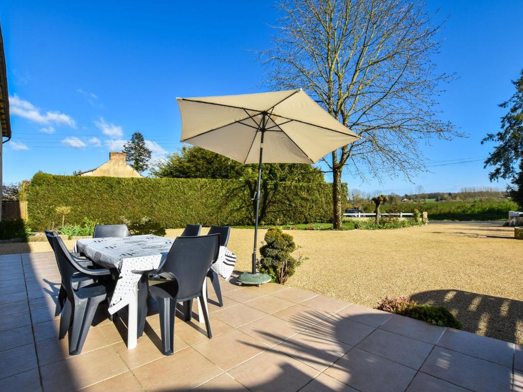 a table and chairs with an umbrella on a patio at Holiday home with pretty terrace and garden, near the Paimpont forest in Lanrelas