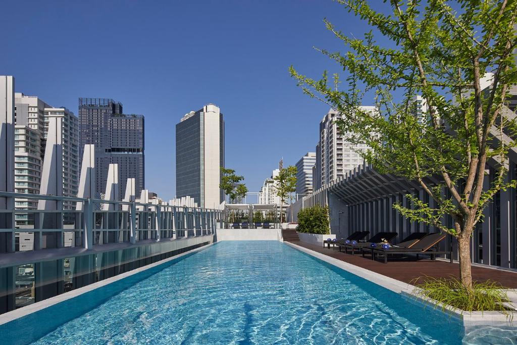 a swimming pool on the roof of a building with a city at Somerset Maison Asoke in Bangkok