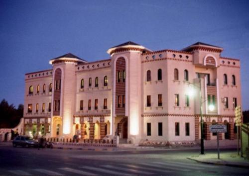 un gran edificio blanco con una luz de la calle delante de él en Résidence El Arich, en Tozeur