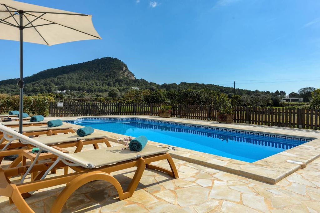 a swimming pool with two chairs and an umbrella at Villa Los Naranjos in Cala Llonga