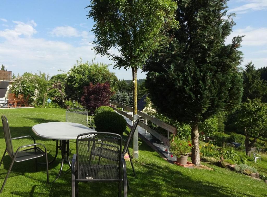 a table and chairs in a yard with a tree at Ferienwohnung Pöhlmann in Bad Lobenstein