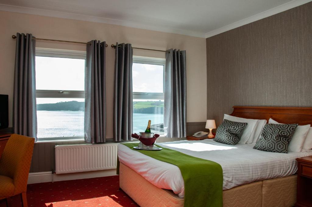 a hotel room with a bed and two windows at Porth Avallen Hotel in St Austell