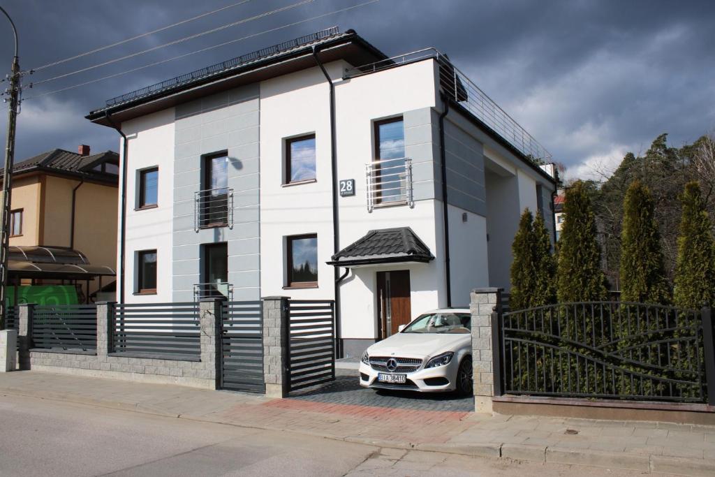 a white house with a car parked in front of it at Willa Kormoran in Augustów