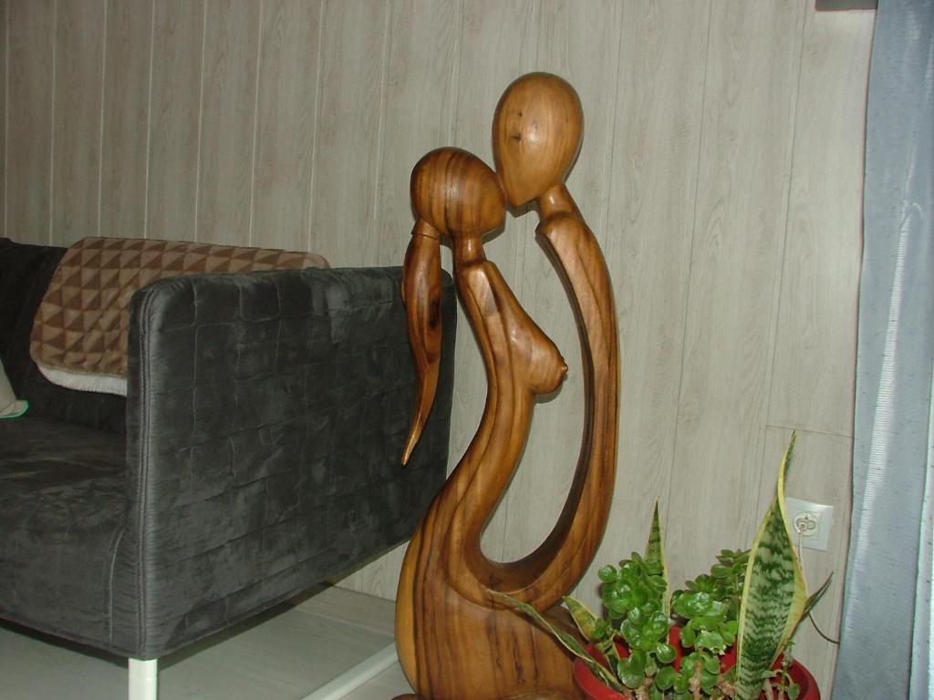 a wooden statue of two people standing next to a couch at le frangipanier in Le Barroux