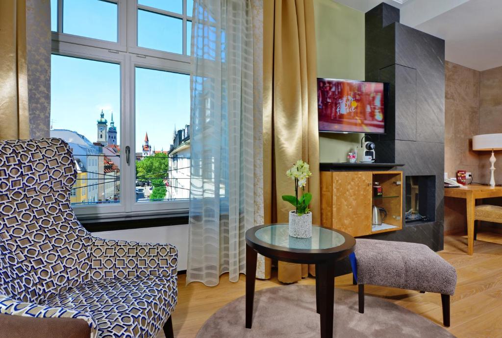 ein Wohnzimmer mit einem Stuhl, einem Tisch und einem Fenster in der Unterkunft Hotel Torbräu in München