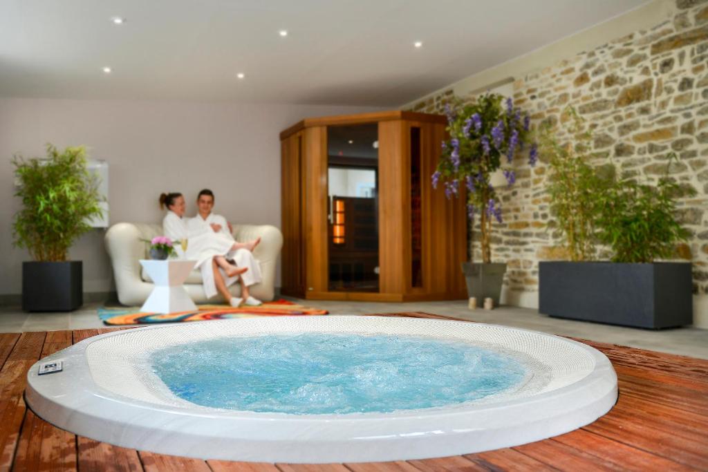 a large swimming pool in a living room with two people at Logis Hotel Au Site Normand in Clécy