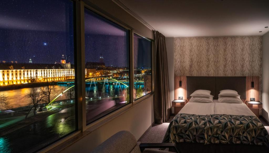 a hotel room with a bed and a view of a city at HP Park Plaza in Wrocław