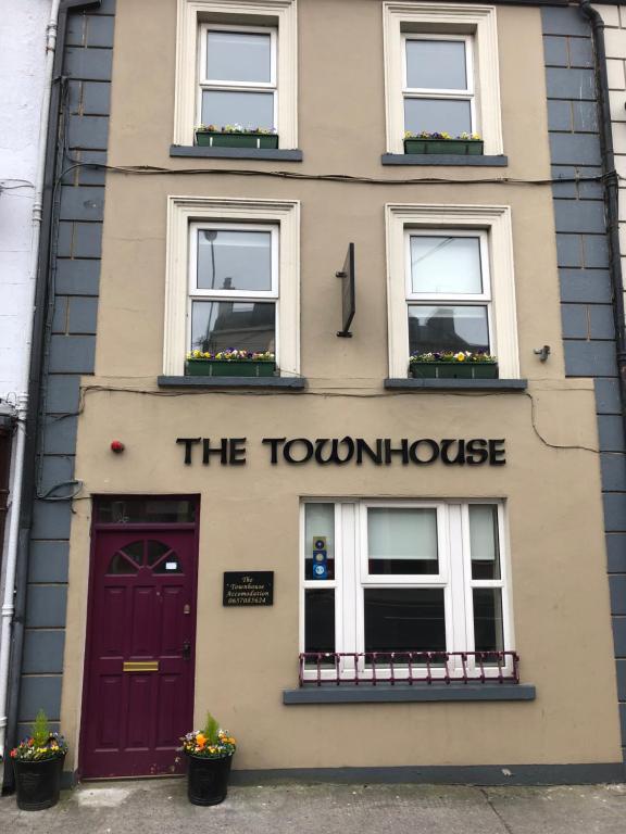 a building with a red door and windows at The Townhouse in Miltown Malbay